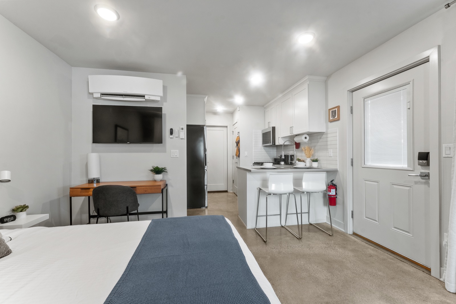 Studio toward the entry — desk, smart TV, and kitchen